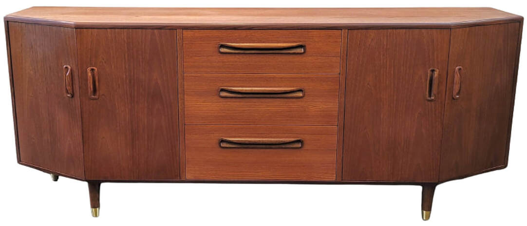 The Fresco canted credenza debuted G-Plan's New Models Folder of 1980.  This buffet base could be paired at the time with an optional buffet top designed for the unit.  Many Fresco Range pieces were designed by Victor Bramwell ( V.B. ) Wilkins.  The credenza is fitted with double-doored canted cabinets to the left and right and three storage drawers down the center. The top drawer is fitted with spacers and lined for flatware storage.  The credenza is veneered with Southeast Asian Crown Cut New Growth Teak.  The trim and inset pulls are of African Afrormosia wood.