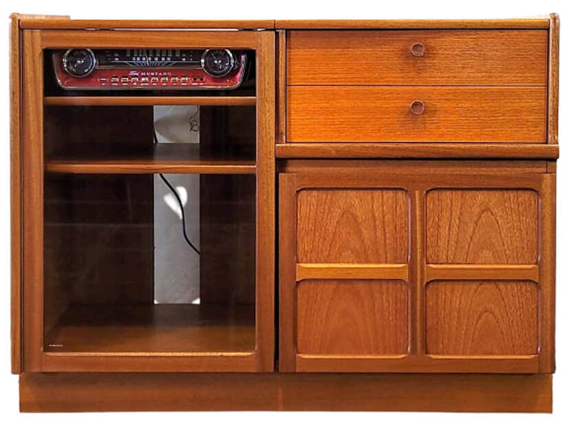 Nathan Furniture Classic Teak range Home Entertainment Unit 5104 from 1991 through 2001 contains on the left a stereo cabinet with a lift top and two adjustable and removable shelves behind a framed door with toughened glass; on the right is one deep drawer with a faux two-drawer front for CD and cassette tape storage and below is a cabinet for storing vinyl records.  The record cabinet door features Jacobean inspired simplified cruciform framed paneling designed by Patrick Lee for Nathan Furniture in 1971. This design was an instant hit when it debuted and has remained an icon of Nathan Furniture collected by generations.