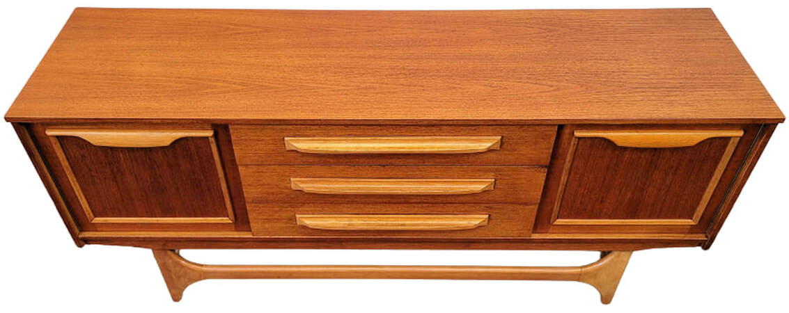 Vintage credenza from England is from Stonehill Furniture's Danish Modern influenced Stateroom range.  Credenza is constructed teak veneers and birch wood solids.  The top features a beautiful cut of Southeast Asian crown-cut teak.  The door and drawer pulls, front trestle base, side stretchers, and door panel framing are birch wood.  Credenza has one single door cabinet on each front end and three stacked drawers in the center.  The cabinets are lined with mottled sapeli wood from Africa and each cabinet contains one removeable sapeli wood shelf.  63.5